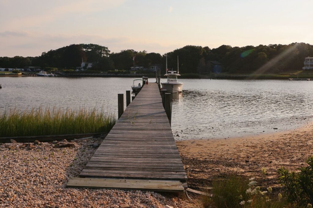 Photo by Sarah O'Shea Serene wooden pier at sunset in Hampton Bays, NY, leading to calm waters.