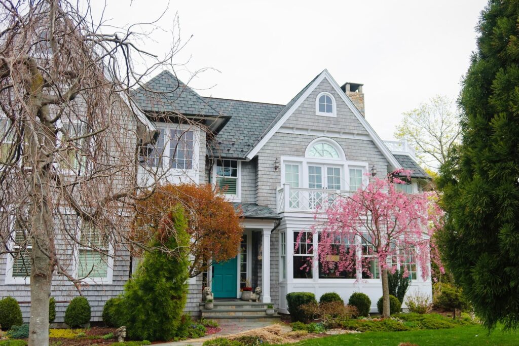 Photo by Daniela Risco Beautiful suburban house with blooming spring trees and classic architecture.