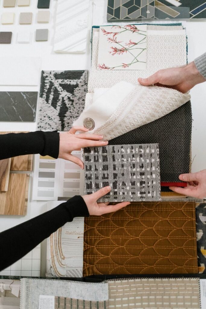 Photo by cottonbro studio Hands selecting fabric samples for interior design projects.