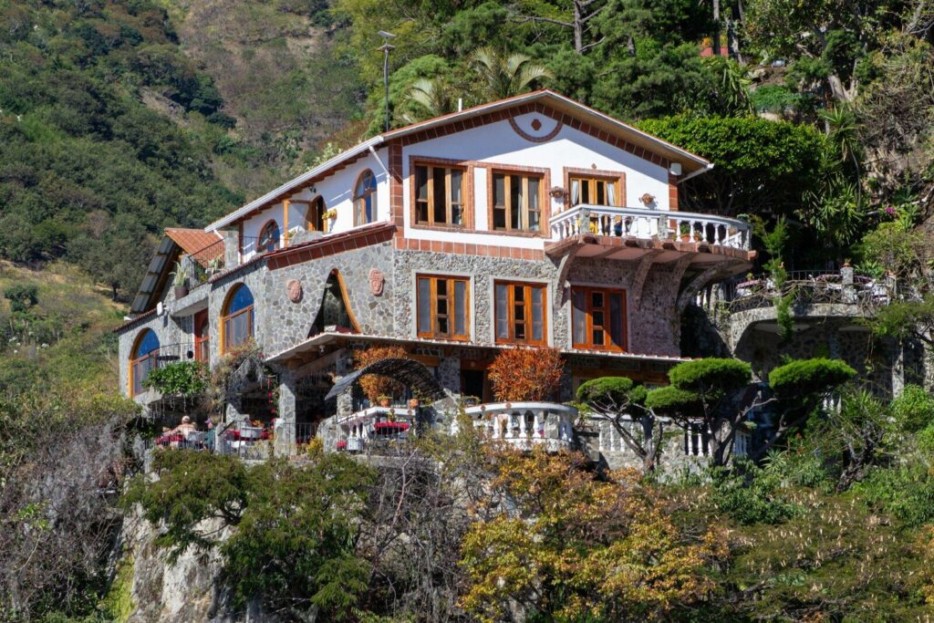 Photo by sebastian alvarado rojas A large stone house on a steep, green hillside.